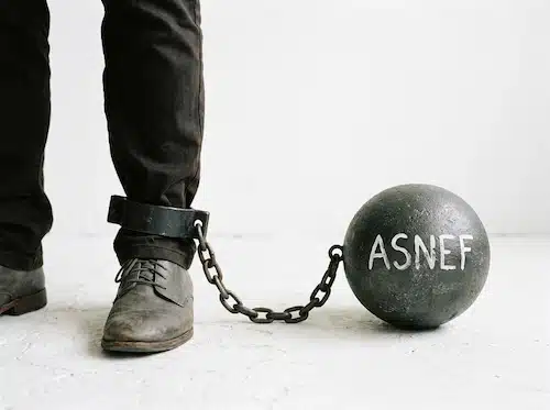a person's lower leg and foot, shackled to a large, dark gray ball with the word ASNEF